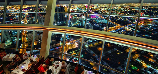 View from 108 Drinks at The Strat; restaurant seating on the bottom left with windows open to Las Vegas Strip